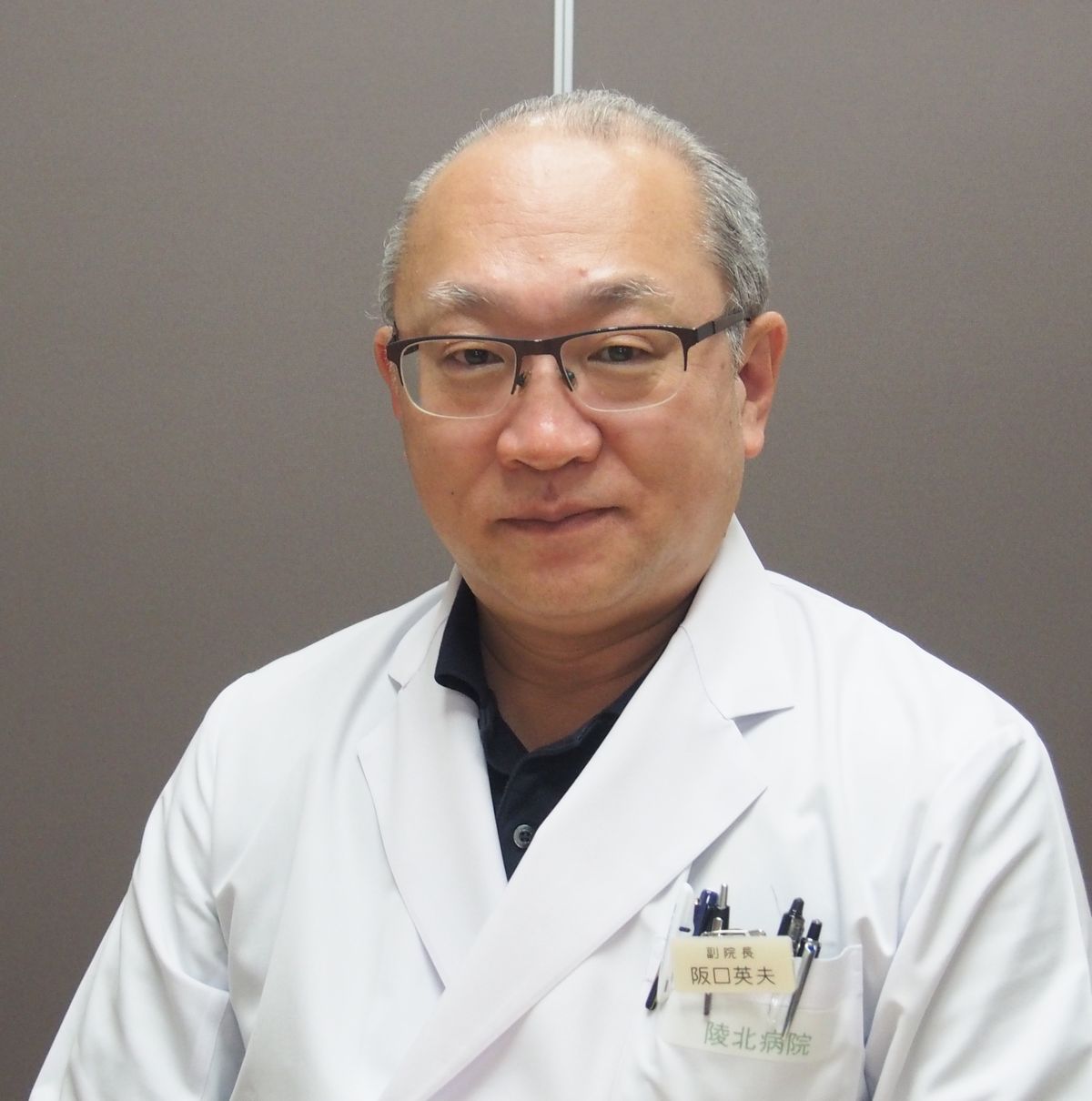大会長坂口先生の正面の写真，背景グレーの壁